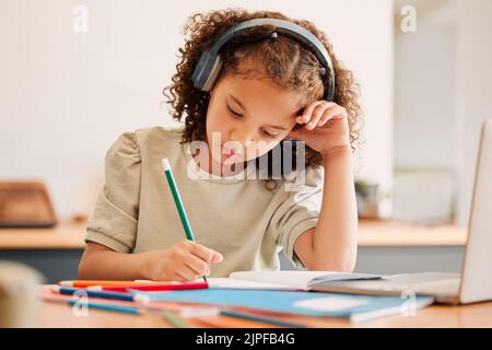 Enfant d'école intelligente, étudiant apprentissage virtuel tout en écrivant dans son livre dans une classe d'éducation. Créativité avec des écouteurs dessinant des œuvres sur papier Banque D'Images