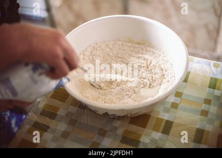 Grand-mère versant du lait dans de la pâte à crêpes Banque D'Images