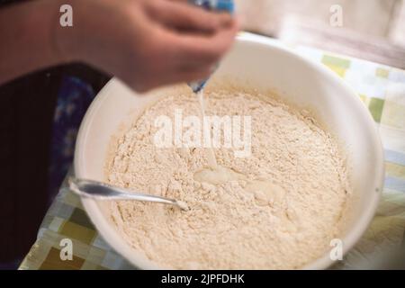 Grand-mère versant du lait dans de la pâte à crêpes Banque D'Images