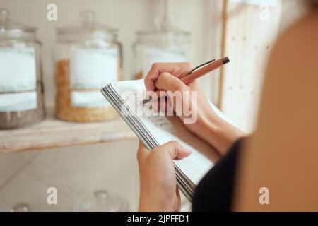 Inventaire des stocks des entrepreneurs et rédaction ou planification d'une liste d'achats dans un magasin sur un bloc-notes. Propriétaire de petite entreprise faisant un budget pour l'inventaire et Banque D'Images