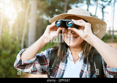 Randonnée touristique féminine, en regardant à travers des jumelles les oiseaux sauvages dans les arbres. Une femme heureuse, insouciante et mûre sur la promenade de la nature, appréciant la vue Banque D'Images