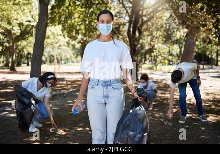 Covid, masque facial et travailleur bénévole nettoyant le parc, faisant le service communautaire et aidant à ramasser les déchets et les bouteilles en plastique. Soutenir l'équipe de militants Banque D'Images