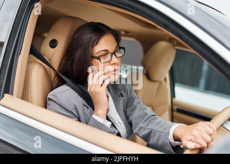 Bien avoir à déplacer cette réunion, mi coincé dans la circulation. Une femme d'affaires parlant sur son téléphone tout en conduisant sa voiture. Banque D'Images