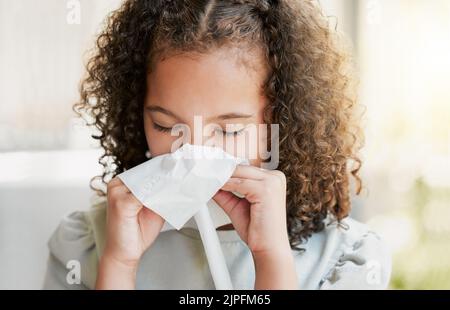 Malade, le nez de nettoyage avec des tissus et une petite fille fatiguée souffrant du virus de la grippe, du rhume ou du covid à la maison. Gros plan d'un jeune enfant avec une mauvaise allergie ou Banque D'Images