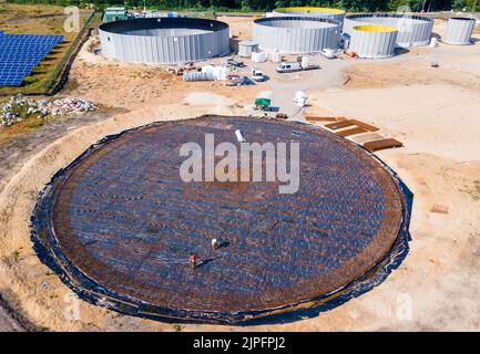 Torgelow, Allemagne. 16th août 2022. Les travailleurs y posent de l'acier de renforcement pour la fondation d'un autre grand réservoir d'un diamètre de plus de 30 mètres pour la future usine de biogaz. (Vue aérienne avec un drone) l'usine de la société Mele Biogas, qui comprend jusqu'à présent six réservoirs de stockage, sera élargie pour doubler sa capacité d'ici l'automne 2023. Selon l'Association d'État de Mecklembourg-Poméranie-Occidentale pour l'énergie renouvelable, un volume d'énergie de plus de 100 millions de kilowattheures par an doit être produit ici et alimenté également dans le réseau de gaz naturel. Credit: Jens Büttner/dpa/Alay Live News Banque D'Images
