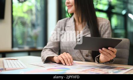 Vue rognée des graphistes travaillant avec des échantillons de couleurs et une tablette numérique dans un bureau moderne Banque D'Images