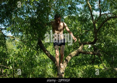 Guy à l'ombre des plantes sans vêtements. Homme en été. Banque D'Images