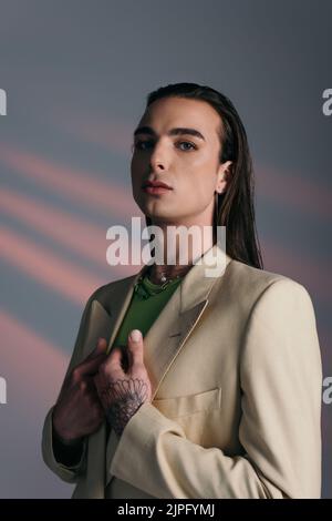 Portrait de la personne de brunette queer en veste debout sur fond abstrait Banque D'Images