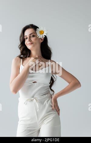 Modèle souriant en vêtements blancs et camomille en cheveux isolés sur gris Banque D'Images