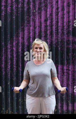 Vieux caucasien vieille femme âgée portrait gris cheveux faisant des exercices avec des haltères à l'extérieur Banque D'Images
