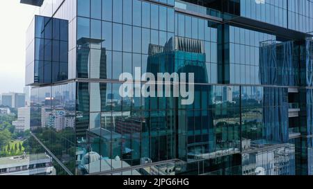 Survol vertical des drones parmi les gratte-ciels futuristes modernes du centre d'affaires de Jakarta City, reflet du coucher de soleil dans une façade en verre brillant Banque D'Images