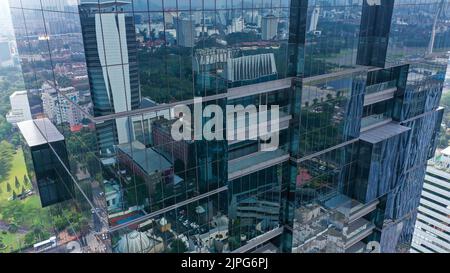 Survol vertical des drones parmi les gratte-ciels futuristes modernes du centre d'affaires de Jakarta City, reflet du coucher de soleil dans une façade en verre brillant Banque D'Images