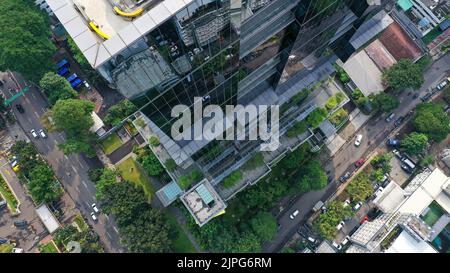 Survol vertical des drones parmi les gratte-ciels futuristes modernes du centre d'affaires de Jakarta City, reflet du coucher de soleil dans une façade en verre brillant Banque D'Images