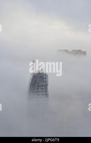 Le sommet d'un gratte-ciel en construction s'élève du brouillard à Benidorm, en Espagne Banque D'Images