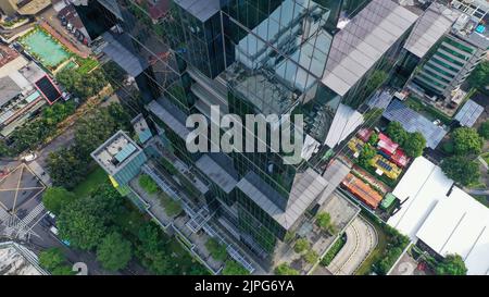 Survol vertical des drones parmi les gratte-ciels futuristes modernes du centre d'affaires de Jakarta City, reflet du coucher de soleil dans une façade en verre brillant Banque D'Images