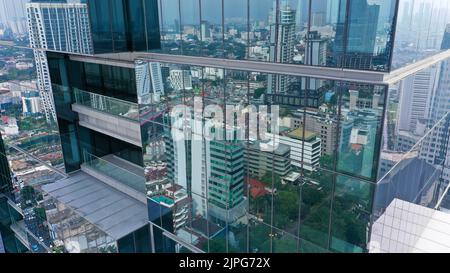 Survol vertical des drones parmi les gratte-ciels futuristes modernes du centre d'affaires de Jakarta City, reflet du coucher de soleil dans une façade en verre brillant Banque D'Images