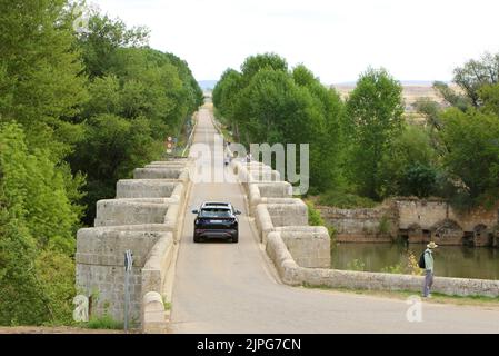 Pont romain au-dessus de la rivière Pisuerga avec un passage à niveau et un homme debout regardant sur un chaud jour d'été Lantadilla Palencia Espagne Banque D'Images