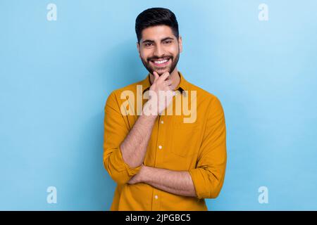 Photo de la barbe funky millenny Guy main visage porter chemise marron isolé sur fond bleu Banque D'Images