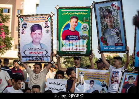 Les Palestiniens et les enfants tiennent des pancartes avec des messages et des photos des enfants tués, appelant à la protection des enfants lors d'une veillée sur le site où 5 enfants de la famille Najm ont été tués lors de la dernière attaque israélienne sur Gaza. Les Palestiniens tiennent une veillée au cimetière de Falloujah près du camp de réfugiés de Jabalia, dans le nord de la bande de Gaza. Cette veillée intervient à la suite de la reconnaissance par les autorités israéliennes du meurtre de cinq enfants dans une attaque aérienne israélienne sur le cimetière de Fallujah, à l'ouest du camp de réfugiés de Jabalia, dans le nord de la bande de Gaza. Banque D'Images