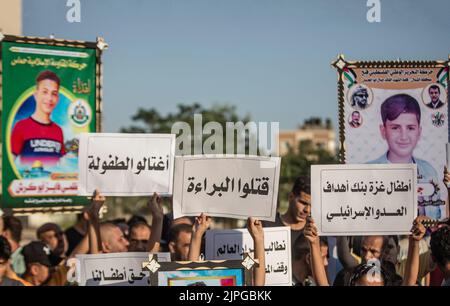 Les Palestiniens et les enfants tiennent des pancartes avec des messages et des photos des enfants tués, appelant à la protection des enfants lors d'une veillée sur le site où 5 enfants de la famille Najm ont été tués lors de la dernière attaque israélienne sur Gaza. Les Palestiniens tiennent une veillée au cimetière de Falloujah près du camp de réfugiés de Jabalia, dans le nord de la bande de Gaza. Cette veillée intervient à la suite de la reconnaissance par les autorités israéliennes du meurtre de cinq enfants dans une attaque aérienne israélienne sur le cimetière de Fallujah, à l'ouest du camp de réfugiés de Jabalia, dans le nord de la bande de Gaza. Banque D'Images