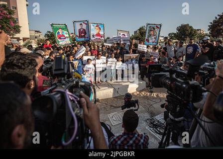 Le personnel des médias enregistre que les Palestiniens et les enfants tiennent des pancartes avec des messages et des photos des enfants tués, appelant à la protection des enfants lors d'une veillée sur le site où 5 enfants de la famille Najm ont été tués lors de la dernière attaque israélienne sur Gaza. Les Palestiniens tiennent une veillée au cimetière de Falloujah près du camp de réfugiés de Jabalia, dans le nord de la bande de Gaza. Cette veillée intervient à la suite de la reconnaissance par les autorités israéliennes du meurtre de cinq enfants dans une attaque aérienne israélienne sur le cimetière de Fallujah, à l'ouest du camp de réfugiés de Jabalia, dans le nord de la bande de Gaza. Banque D'Images