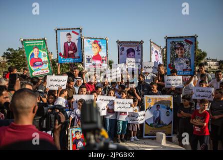 Les Palestiniens et les enfants tiennent des pancartes avec des messages et des photos des enfants tués, appelant à la protection des enfants lors d'une veillée sur le site où 5 enfants de la famille Najm ont été tués lors de la dernière attaque israélienne sur Gaza. Les Palestiniens tiennent une veillée au cimetière de Falloujah près du camp de réfugiés de Jabalia, dans le nord de la bande de Gaza. Cette veillée intervient à la suite de la reconnaissance par les autorités israéliennes du meurtre de cinq enfants dans une attaque aérienne israélienne sur le cimetière de Fallujah, à l'ouest du camp de réfugiés de Jabalia, dans le nord de la bande de Gaza. Banque D'Images