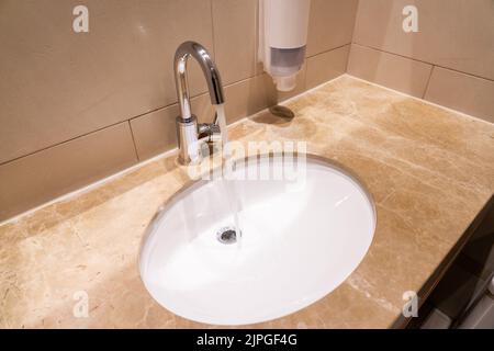 L'eau coule d'un robinet dans un évier dans un intérieur moderne Banque D'Images