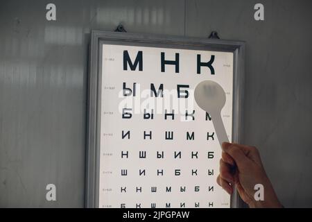 Médecin opticien avec un tableau de lettres pour la vérification du test de la vision oculaire. Banque D'Images