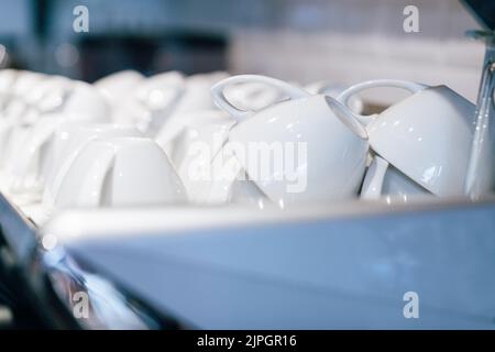 Une pile de tasses blanches sur le dessus d'une machine à café Banque D'Images