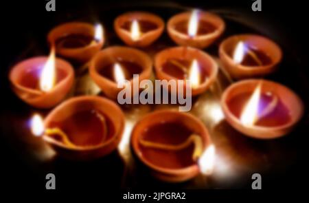 Un flou Macro prises de vues de diyas étant illuminées à la main ou à la bougie pour le festival religieux hindou de Diwali Banque D'Images