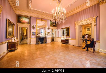 Une grande cheminée avec un grand miroir et de vieux tableaux de maître sur les murs. Une garde montres. Au Wallace Collection Museum de Londres, Angleterre, United Banque D'Images