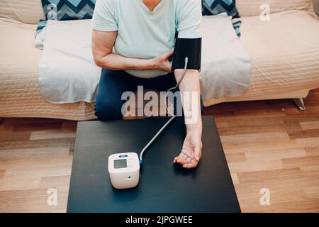 Femme âgée prenant des mesures de tension artérielle à la maison à l'intérieur.Soins personnels de santé des personnes âgées. Banque D'Images