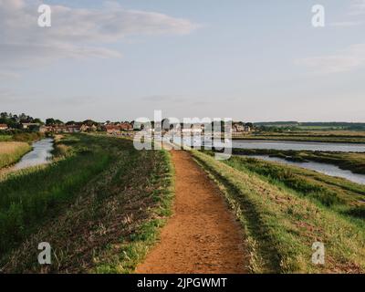 Marcher sur le sentier côtier surélevé de Norfolk jusqu'à Burnham Overy dans le paysage de marais d'été de la côte nord de Norfolk Angleterre Banque D'Images