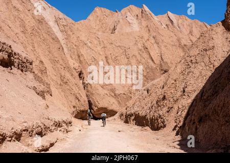 Deux motards de montagne passent sur le sentier dans la gorge du diable ou Garganta del Diablo dans le désert d'Atacama au Chili. Banque D'Images