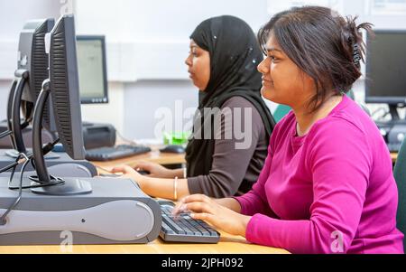 Travail informatique. Des collègues adultes matures travaillent ensemble dans un environnement de bureau ouvert. D'une série d'images avec le même thème. Banque D'Images