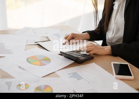 Gros plan femme d'affaires utilisant la calculatrice pour faire des mathématiques de finances sur table en bois dans le bureau et le travail d'affaires fond. Impôts, comptabilité, statistiques et Banque D'Images