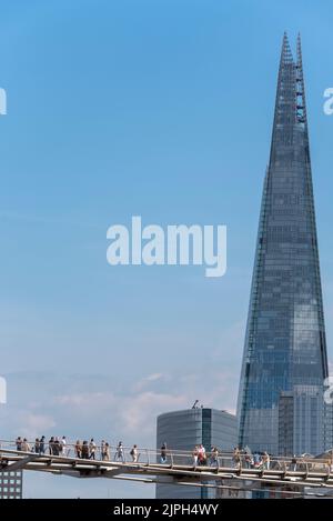 Les gens qui traversent le pont du millénaire au-dessus de la Tamise, Londres, Royaume-Uni, devant les hauts développements et le gratte-ciel de Shard. Echelle Banque D'Images