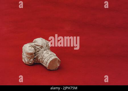 L'appareil photo avec un grand objectif est enveloppé dans du papier kraft, attaché avec du cordon. Sur fond rouge. Cadeau pour photographe Banque D'Images