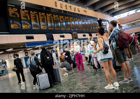 Les passagers pleins d'espoir regardent le panneau des départs à la gare d'Euston pendant une autre journée de grève ferroviaire par le syndicat des travailleurs ferroviaires de la RMT, le 18th août 2022, à Londres, en Angleterre. Plus de 45 000 travailleurs du rail sont sortis d'affilée au sujet de salaires, d'emplois et de conditions. Les passagers des trains ont été confrontés à davantage de perturbations, avec seulement 20 % des services en cours jeudi, mais deux jours supplémentaires d'action industrielle impliquant des employés d'autobus et de métro. Banque D'Images