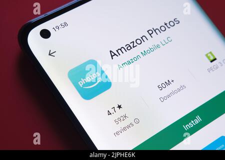 Application photos Amazon vue dans Google Play Store sur l'écran du smartphone placé sur un arrière-plan rouge. Gros plan avec mise au point sélective. Stafford, Royaume-Uni Banque D'Images