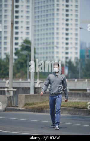 Jeune homme en masque souffrant d'une grave pollution de l'air Banque D'Images