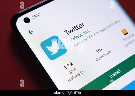 Application twitter vue dans Google Play Store sur l'écran du smartphone placé sur fond rouge. Gros plan avec mise au point sélective. Stafford, Royaume-Uni Banque D'Images