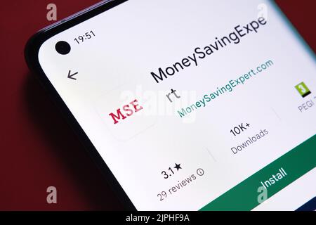 Application moneysavingexpert vue dans Google Play Store sur l'écran du smartphone placé sur fond rouge. Gros plan avec mise au point sélective. Stafford, unité Banque D'Images
