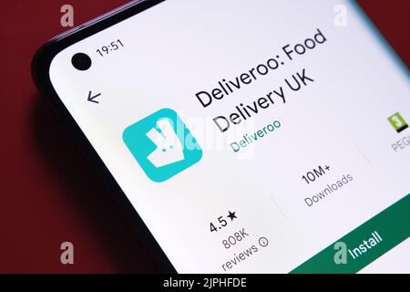 application deliveroo affichée dans Google Play Store sur l'écran du smartphone placé sur un arrière-plan rouge. Gros plan avec mise au point sélective. Stafford, Royaume-Uni Banque D'Images