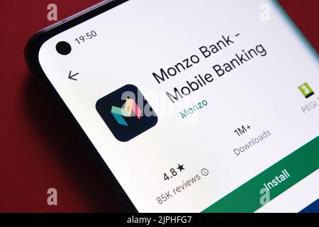 Application Monzo vue dans Google Play Store sur l'écran du smartphone placé sur fond rouge. Gros plan avec mise au point sélective. Stafford, Royaume-Uni, Banque D'Images