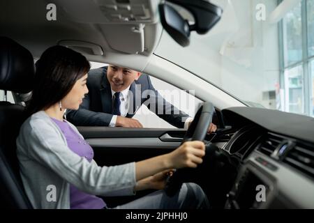 Vendeur parlant à une cliente assise dans la voiture Banque D'Images