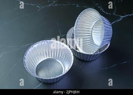 Tas de moules à gâteau de muffins en aluminium vides isolés sur la table de cuisine Banque D'Images