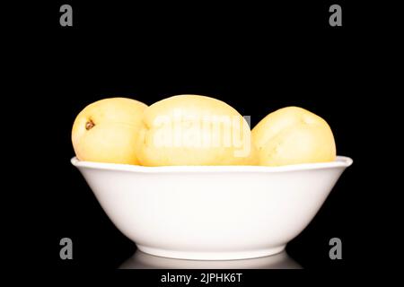 Trois abricots jaune vif juteux d'ananas dans une poterie, macro, isolés sur un fond noir. Banque D'Images