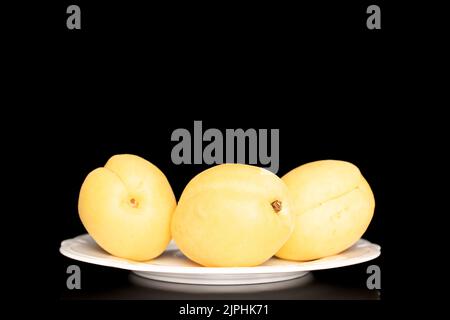 Trois abricots jaune vif juteux d'ananas dans une poterie, macro, isolés sur un fond noir. Banque D'Images