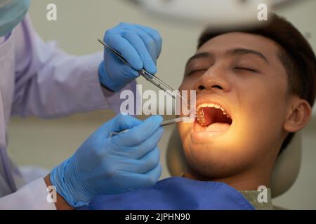 Jeune homme vietnamien ayant examiné ses dents au cabinet du dentiste Banque D'Images